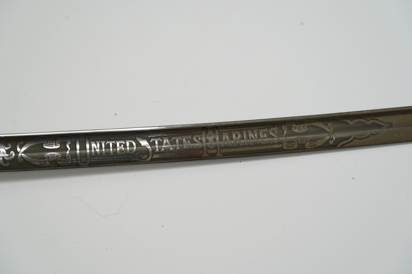 A 1954 US Marine Wilkinson Sword belonging to Staff Sergeant James Devereux 2nd believed to be son of General Devereux, etched blade, regulation brass hilt, in its plated scabbard, blade 76.5cm. Condition - good